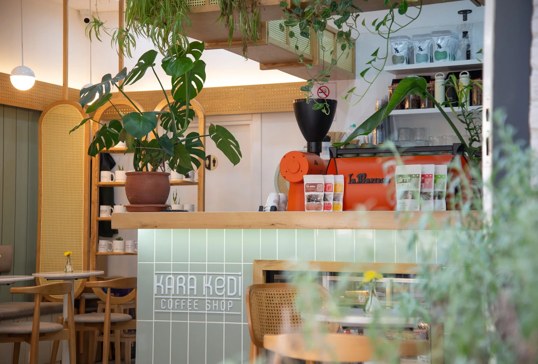 植物とオレンジ色のエスプレッソマシンがあるカフェ店内